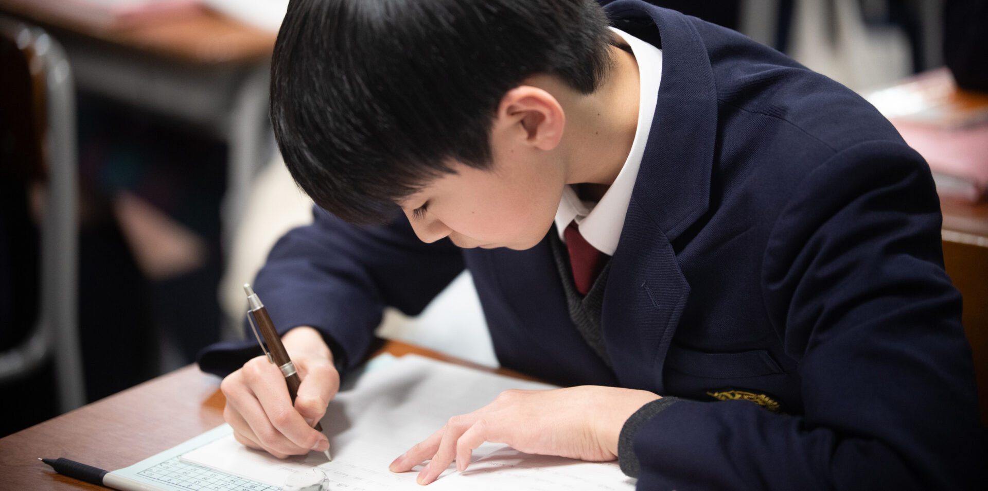 ノートに板書を写す男子学生